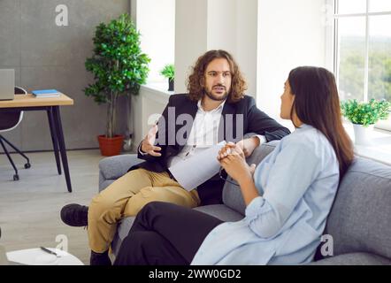 Zwei junge Geschäftspartner diskutieren den Deal, während sie im Büro auf der Couch sitzen Stockfoto
