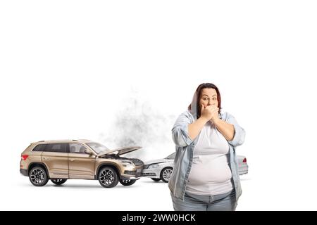 Autounfall und eine schockierte Frau, die den Mund mit isolierten Händen auf blauem Hintergrund bedeckt Stockfoto