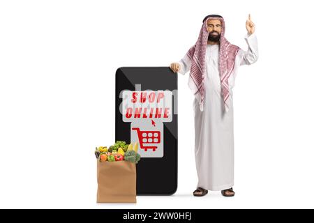 Kaufen Sie online, mobile App auf einem Smartphone und ein sudi arabischer Mann mit einer Einkaufstasche, die auf weißem Hintergrund nach oben zeigt Stockfoto