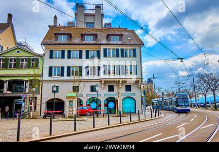 ZÜRICH, SCHWEIZ - 3. APRIL 2022: Moderne Straßenbahnfahrten am Limmatquai-Damm, vorbei an historischen Wohnhäusern, am 3. April in Zürich, Stockfoto