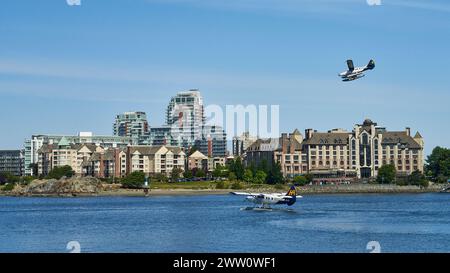 Ein Hafenflugzeug, das vor einigen großen Hotels auf dem Meer herumfährt, mit einem anderen Flugzeug darüber, das zur Landung ankommt. Stockfoto