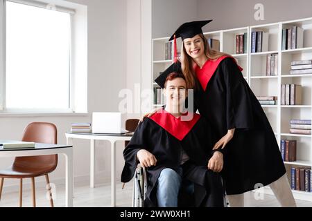 Männlicher Absolvent im Rollstuhl mit Klassenkamerad an der Universität Stockfoto