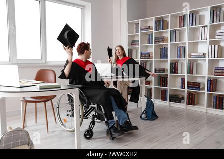 Glücklicher männlicher Absolvent im Rollstuhl mit Klassenkamerad an der Universität Stockfoto