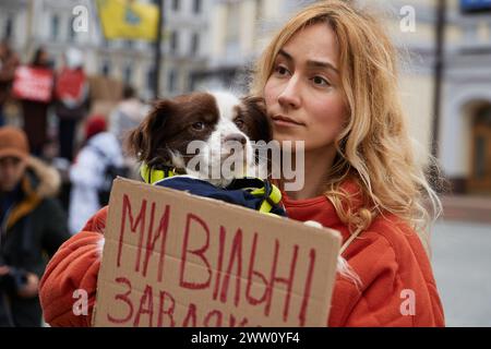 Ein junges ukrainisches Weibchen hält bei einer öffentlichen Demonstration einen Hund und ein Banner "Wir sind frei". Kiew - 17. März 2024 Stockfoto