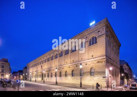 Die Abenddämmerung fällt auf die historische Bibliothek Sainte-Genevieve, in der die Straßenlaternen leuchten. Stockfoto