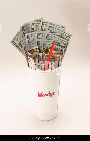 Maplewood, Minnesota. Wendy's Fastfood-Kette. Wendys Soda-Becher mit Geld und einem Strohhalm auf weißem Hintergrund. Stockfoto