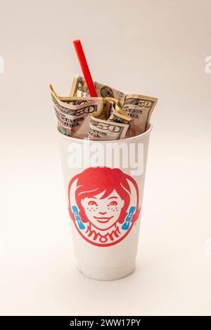 Maplewood, Minnesota. Wendy's Fastfood-Kette. Wendys Soda-Becher mit Geld und einem Strohhalm auf weißem Hintergrund. Stockfoto