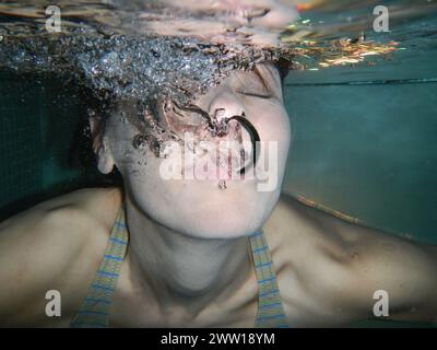 Frauengesicht mit geschlossenen Augen unter Wasser mit Blasen in der Schweiz. Stockfoto