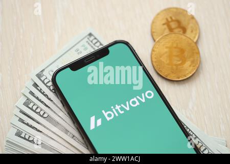 KIEW, UKRAINE - 15. MÄRZ 2024 Bitvavo-Logo auf dem iPhone-Display mit Dollars und Bitcoins auf dem Tisch. Portal für den Austausch von Kryptowährungen Stockfoto