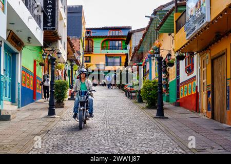 Guatape, Kolumbien - 16. Januar 2023: Man fährt ein Motorrad auf einer kopfsteingepflasterten Straße im Zentrum der Stadt Stockfoto