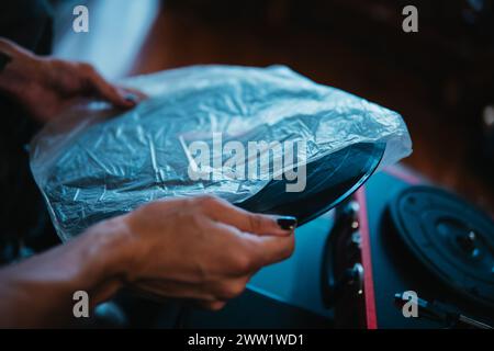 Nahaufnahme einer Hand, die eine Schallplatte auf einem roten tragbaren Plattenspieler platziert Stockfoto