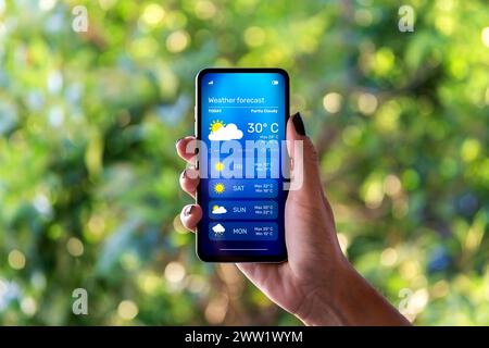 Frau im Freien, die die Wettervorhersage in einer App auf ihrem Handy überprüft. Stockfoto