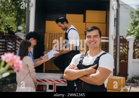 In einem Porträt entlädt ein glücklicher Mover Kisten von einem Lkw in ein neues Zuhause. Diese Arbeiter zeigen Teamarbeit Stockfoto