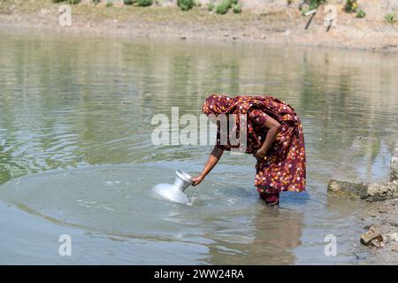 10. März 2024, Dhaka, Bangladesch: Eine Frau, die Trinkwasser aus einem Teich bei Shyamnagar Gabura im Bezirk Satkhira sammelt. In der Gabura Union im Distrikt Shatkhira im Süden von Bangladesch stehen die Einwohner vor einer durch den Klimawandel verschärften katastrophalen Trinkwasserkrise. Menschen, einschließlich Frauen und Kinder, müssen täglich lange Wege zurücklegen, um Zugang zu sicheren Wasserquellen zu erhalten, was die gesundheitlichen Risiken durch durch durch Wasser übertragene Krankheiten erhöht. Daten auf der Ebene der Küstenbezirke zeigen, dass sich erhebliche Prozentsätze mit Wasserknappheit auseinandersetzen, wobei Umweltschützer die Situation als gravierender andeuten. Sinkende unterirdische WA Stockfoto