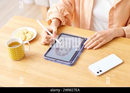 Eine Frau, die mit einem Bleistift auf eine Tablette zeichnet Stockfoto