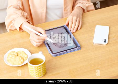 Eine Frau, die mit einem Stift auf eine Tablette zeichnet Stockfoto