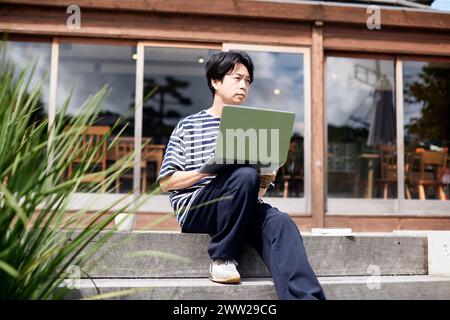 Ein Mann, der mit einem Laptop auf einer Treppe sitzt Stockfoto