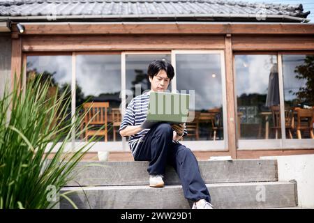 Ein Mann, der mit einem Laptop auf einer Treppe sitzt Stockfoto
