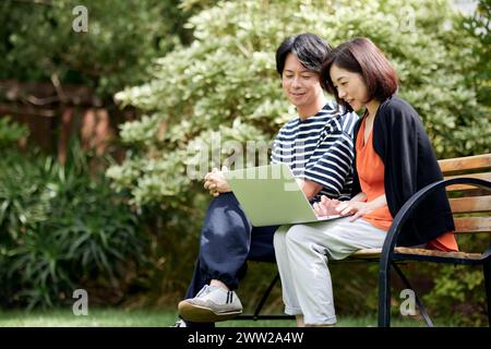 Asiatisches Paar mit Laptop im Garten Stockfoto