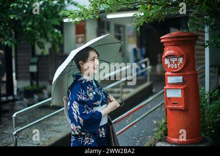 Eine Frau im Kimono, die neben einem Briefkasten steht Stockfoto