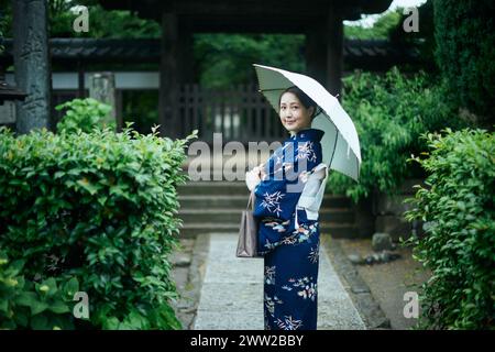 Eine Frau im Kimono, die unter einem Schirm steht Stockfoto