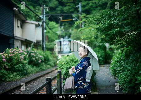 Eine Frau in einem Kimono, die auf einem Bahngleis steht Stockfoto