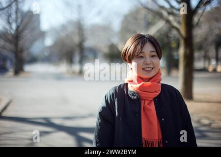 Eine Frau mit Schal und schwarzer Jacke, die mitten auf einer Straße steht Stockfoto