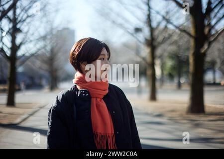 Eine Frau mit Schal und Jacke, die mitten auf einer Straße steht Stockfoto