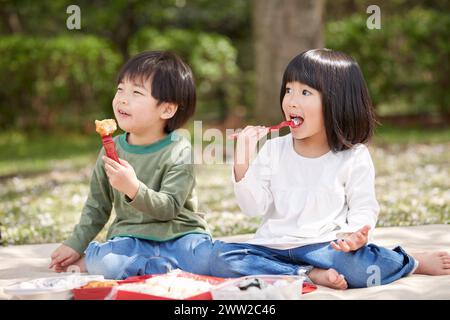 Zwei Kinder sitzen auf dem Boden und essen Essen Stockfoto