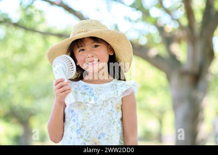 Ein junges Mädchen mit einem Hut, der einen Ventilator hält Stockfoto