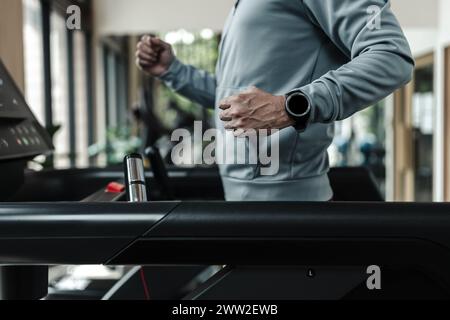 Ein Mann mit intelligenter Uhr, der auf dem Laufband läuft, Fitness treibt. Fitness, Fitnessstudio, Workout und Lifestyle-Konzept. Stockfoto