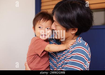 Ein Mann, der ein Baby hält und lächelt Stockfoto