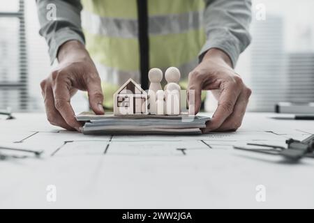 Hausmodell, Holzpuppe und Geld auf dem Grundriss der Familie sparen Geld beim Kauf des Hauses. Architekt- und Ingenieurkonzept. Stockfoto