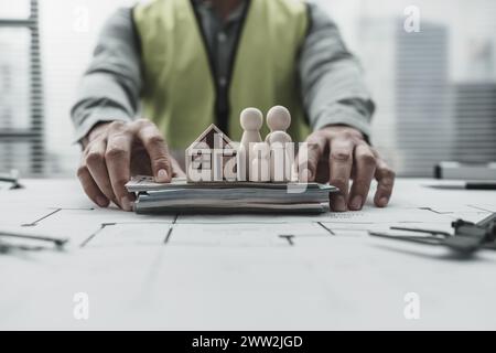 Hausmodell, Holzpuppe und Geld auf dem Grundriss der Familie sparen Geld beim Kauf des Hauses. Architekt- und Ingenieurkonzept. Stockfoto