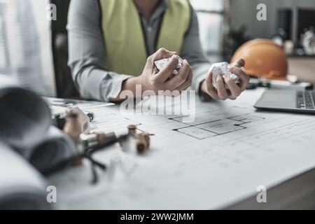 Der Architekt und Ingenieur machte einen Fehler beim Entwurf des Plans. Papier-Crump-Blueprint in der Hand. Fehler, Fehler und Problem Konzept. Stockfoto