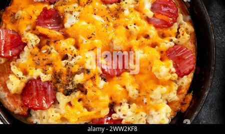 Trendiges Hybrid-Essen. Mac und Käse Pizza auf dunklem Hintergrund. Draufsicht Stockfoto