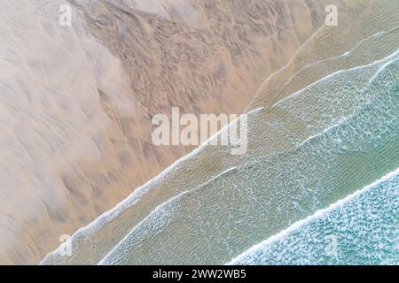 Blick von der Drohne auf den Strand mit Wellen, die bei Ebbe über nassem Sand spülten Stockfoto