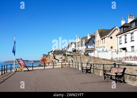 Blick auf traditionelle strohgedeckte Häuser mit Blick auf den Strand am Westende der Stadt mit einem großen Liegestuhl im Vordergrund, Sidmouth, Devon, Großbritannien. Stockfoto