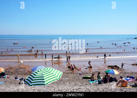 Touristen entspannen sich am Strand mit Blick auf das Meer, Sidmouth, Devon, Großbritannien, Europa. Stockfoto