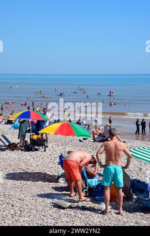 Touristen entspannen am Strand mit Polizeiangeboten auf der rechten Seite und Blick auf das Meer, Sidmouth, Devon, Großbritannien, Europa. Stockfoto