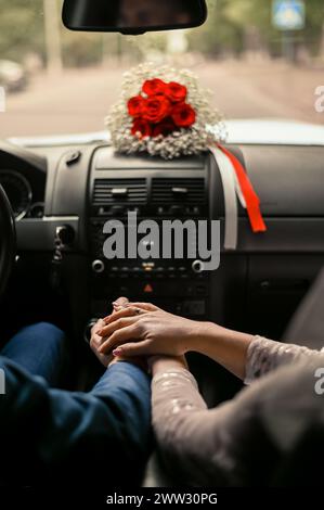 Eine Frau hält die Hand eines Mannes in einem Auto Stockfoto