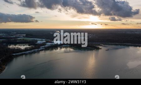 Ein ruhiger See reflektiert die letzten Strahlen der untergehenden Sonne und schafft eine ruhige Szene, die von oben aufgenommen wird. Dramatische Wolken fügen der ansonsten friedlichen Landschaft ein dynamisches Element hinzu und laden zur Reflexion und Bewunderung der Schönheit der Natur ein. Sonnenuntergang über dem ruhigen See mit dramatischem Blick auf den Wolken. Hochwertige Fotos Stockfoto