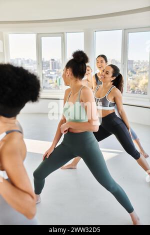 Gruppe glücklicher Frauen in Leggings, die Pilates mit weiblichen afroamerikanischen Trainern üben Stockfoto