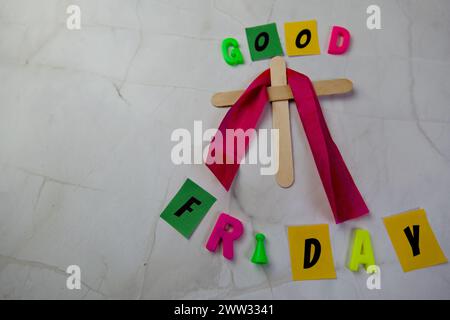 Einfaches Holzkreuz steht aufrecht vor einem sauberen, weißen Hintergrund. Die Worte „Karfreitag“ Stockfoto