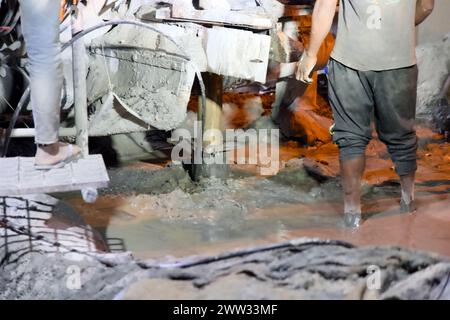 Nahaufnahme einer mechanisierten Bohrlochbohrung, beleuchtet durch künstliche Lichter in einer städtischen Umgebung bei Nacht Stockfoto