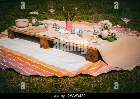 Eine einladende Picknickumgebung im Freien mit künstlerischen Vorräten auf einer rustikalen Holzpalette. Stockfoto