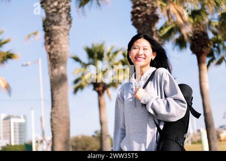 asiatische Frau lächelt beim Gehen mit Yogamatte Stockfoto