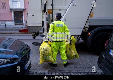 München, Deutschland. März 2024. Ein Mitarbeiter des Entsorgungsunternehmens Wittmann trägt gelbe Beutel zu einem Müllfahrzeug in München. Die Stadt München macht einen Schritt hin zu einer nachhaltigen Abfallwirtschaft. Seit Februar 2024 läuft ein Pilotprojekt mit dem Namen „Yellow Systems“, das bis Ende 2026 laufen wird. Quelle: Lennart Preiss/dpa/Alamy Live News Stockfoto