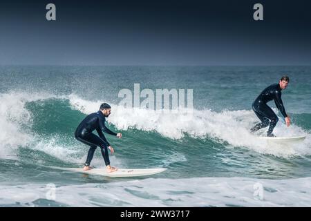 Zwei Surfer auf einer Welle im Fistral in Newquay in Cornwall, Großbritannien. Stockfoto
