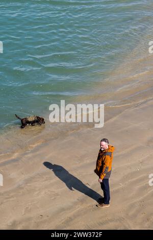 Ein Hundeführer und sein Hund am Towan Beach in Newquay in Cornwall in Großbritannien. Stockfoto